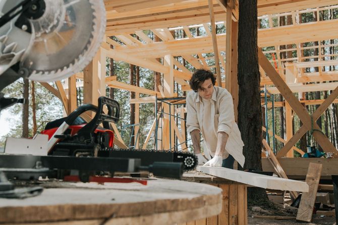 Person cutting wood with a power saw inside a house under construction