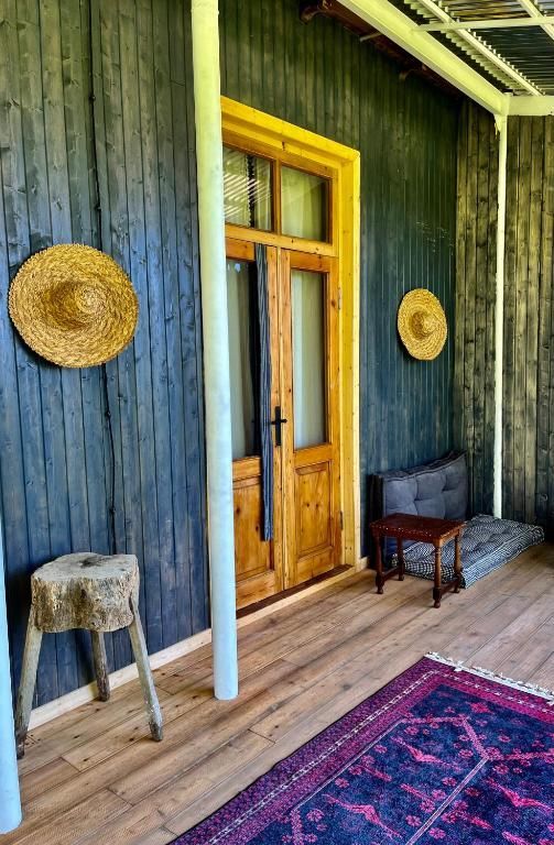 A porch with a wooden door and straw hats on the wall.