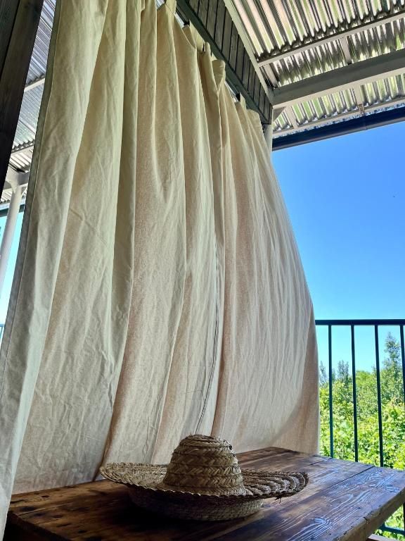 A straw hat is sitting on a wooden table under a white curtain.