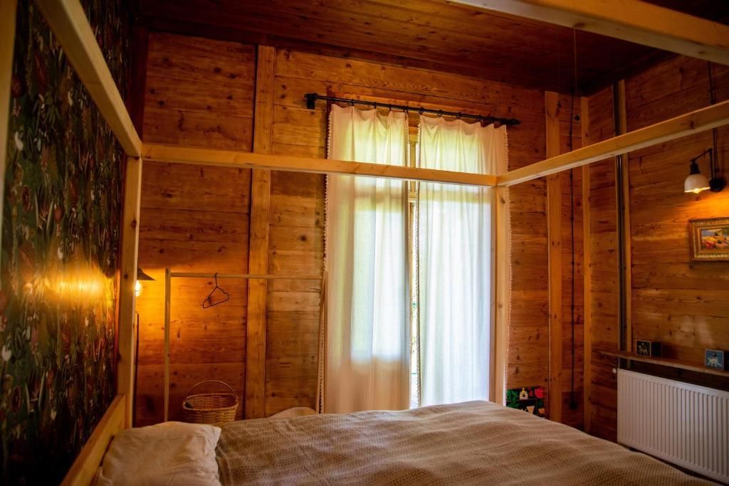 A bedroom with a bed and a window in a wooden house.