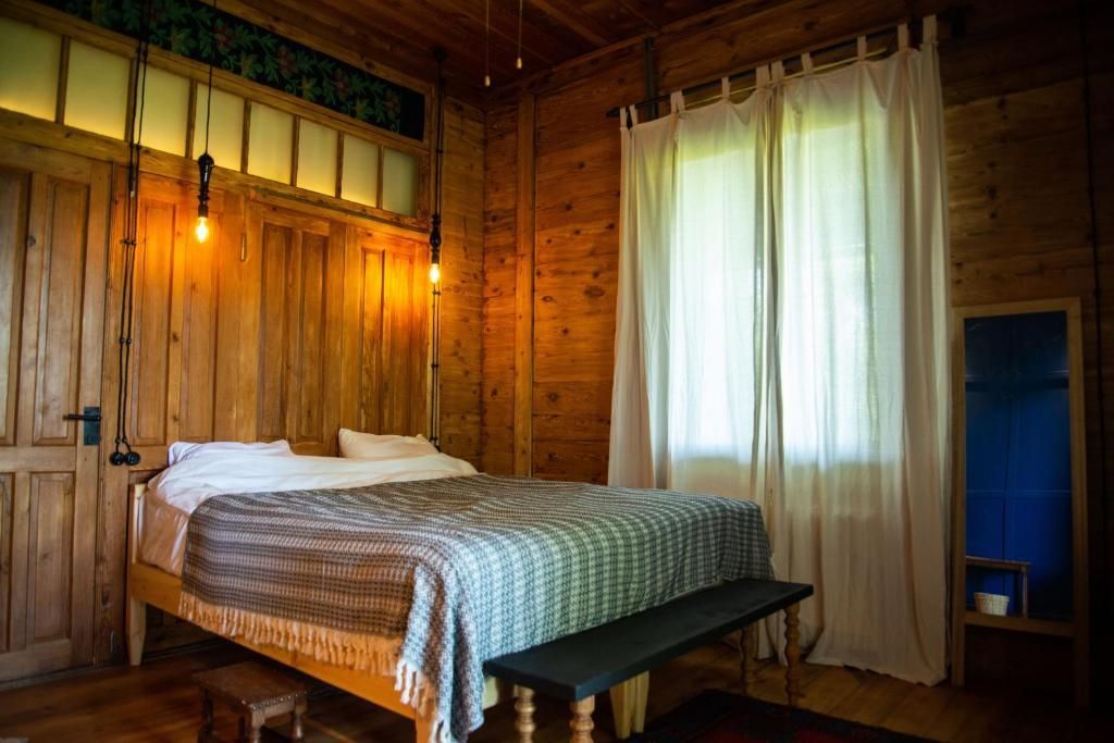 A bedroom in a wooden cabin with a bed and a bench.