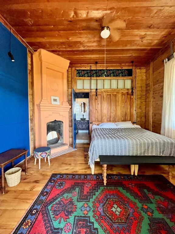 A bedroom with a bed a rug and a fireplace