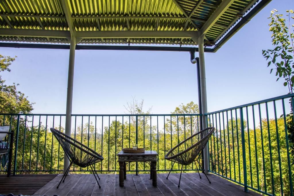 A balcony with two chairs and a table with trees in the background