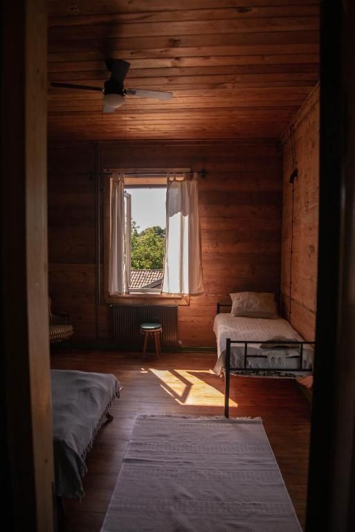 A bedroom with two beds and a window with a ceiling fan.