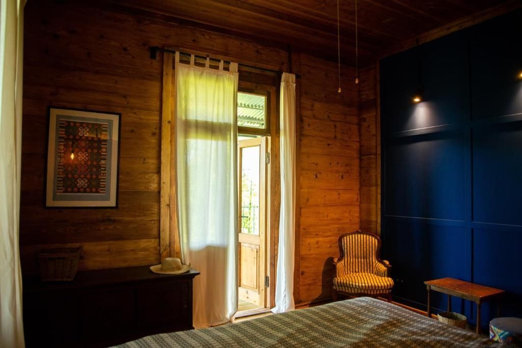 A bedroom with a bed , chair , dresser and window.