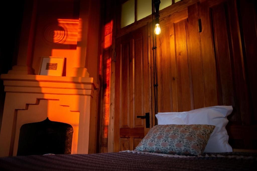 A bedroom with a bed , fireplace and wooden walls.