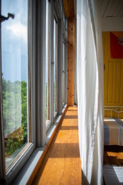 A long hallway with lots of windows and a yellow door leading to a bedroom.