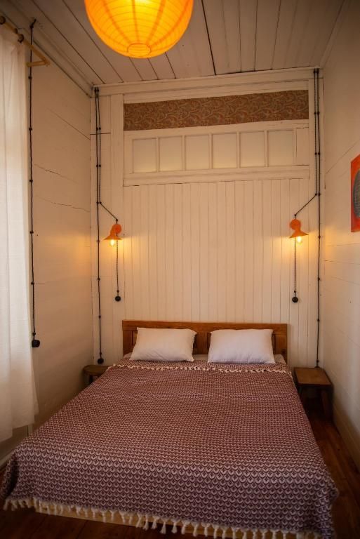 A bedroom with a bed and two lamps on the wall