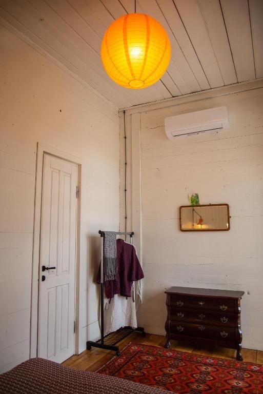 A bedroom with a dresser and a lamp hanging from the ceiling