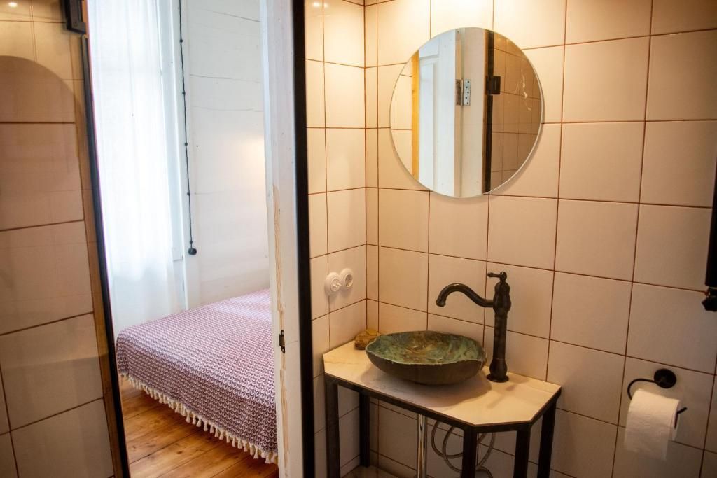 A bathroom with a sink , mirror and a bed.