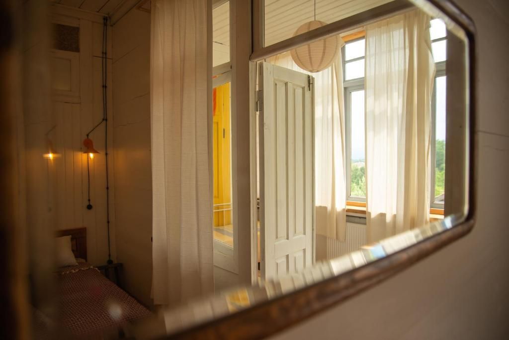 A bedroom with a bed and a window is reflected in a mirror.