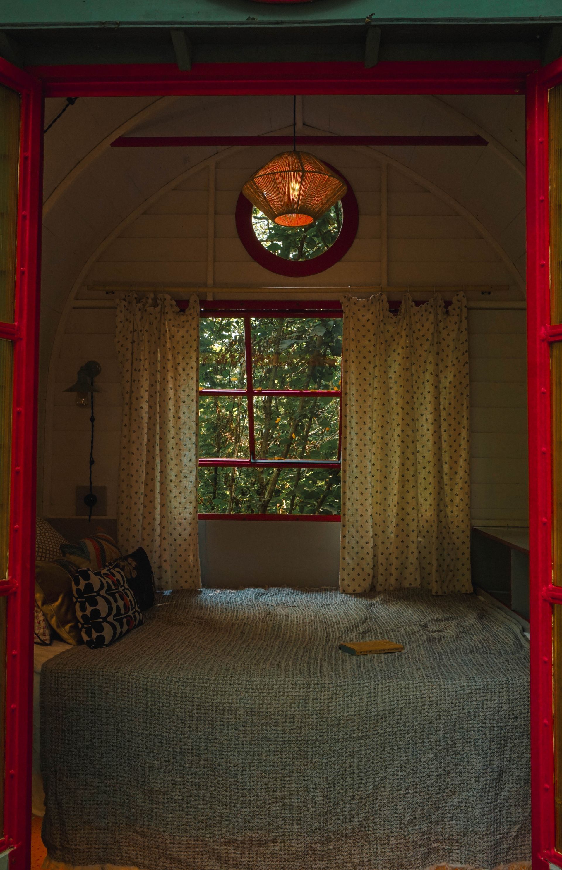 A bedroom with a bed and a window with trees in the background.