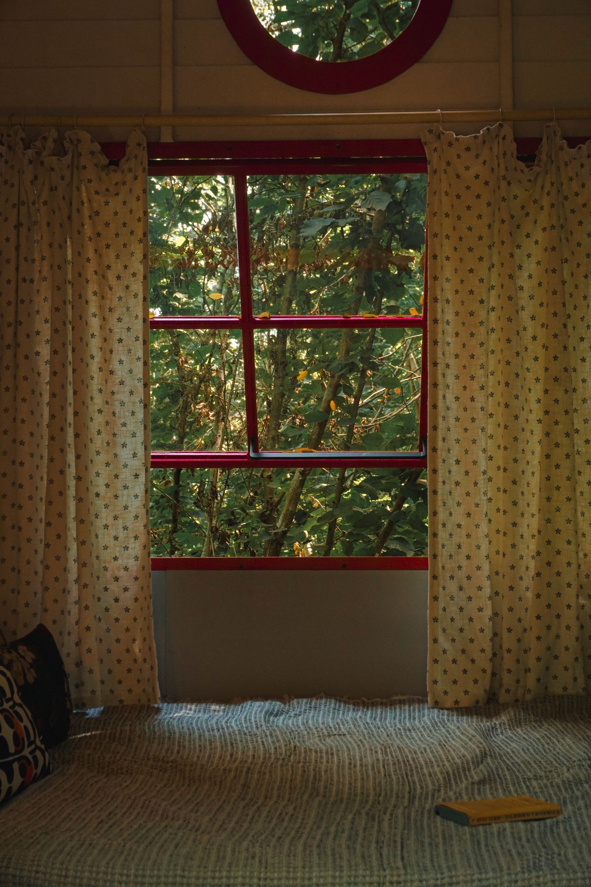 A bedroom with a bed and a window with trees outside