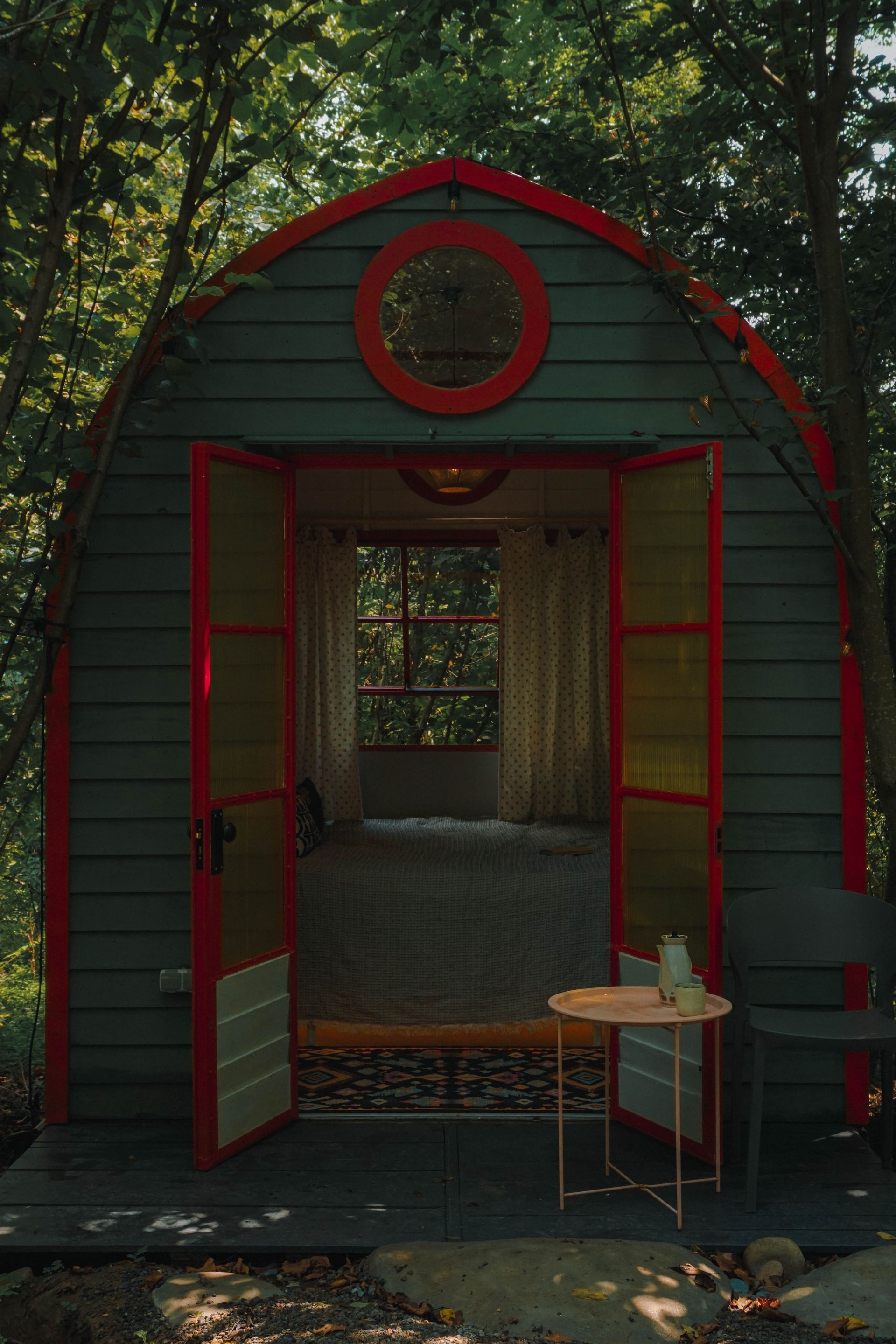 A small house with a red door and a table in front of it.