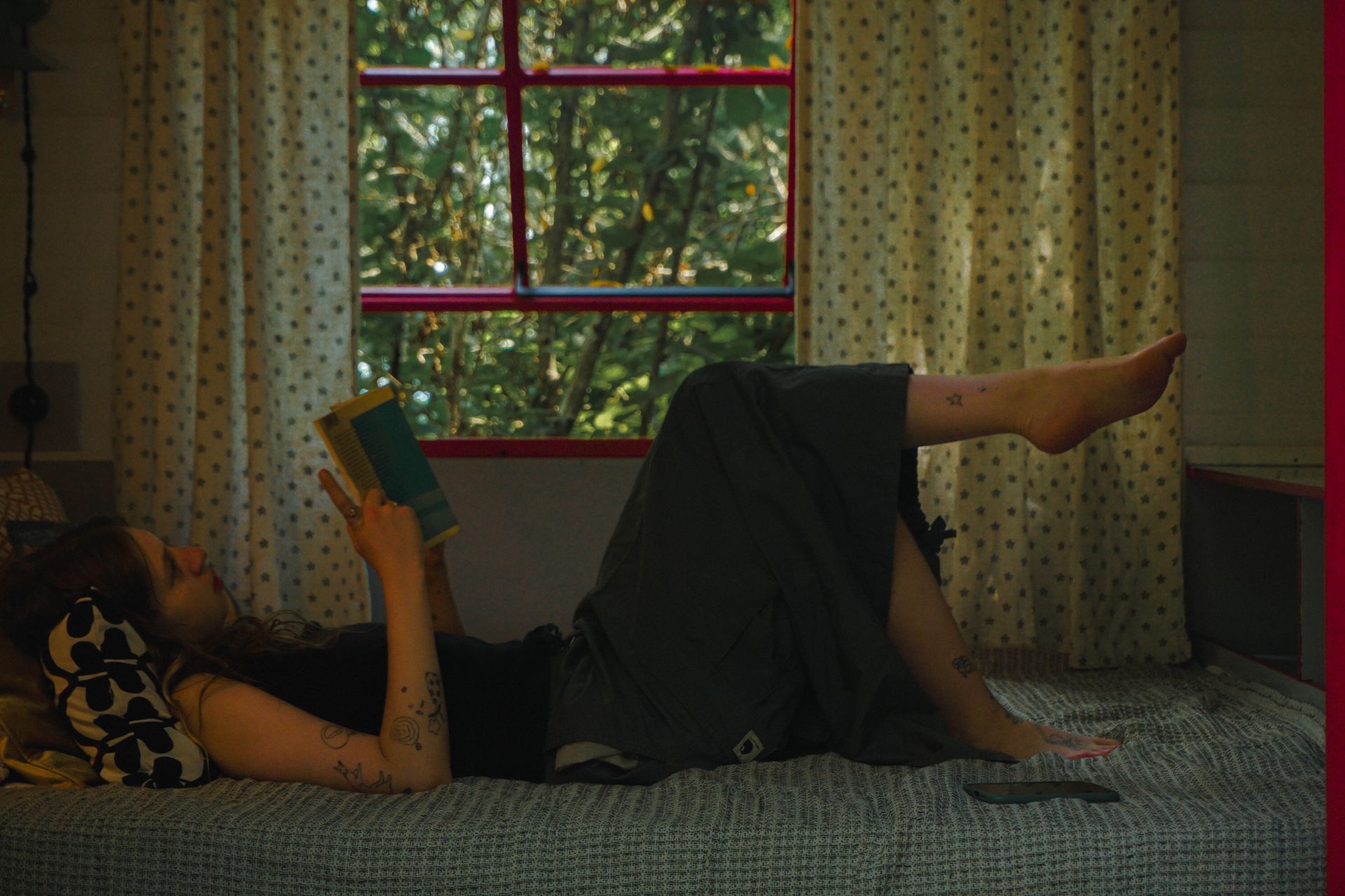 A woman is laying on a bed reading a book.