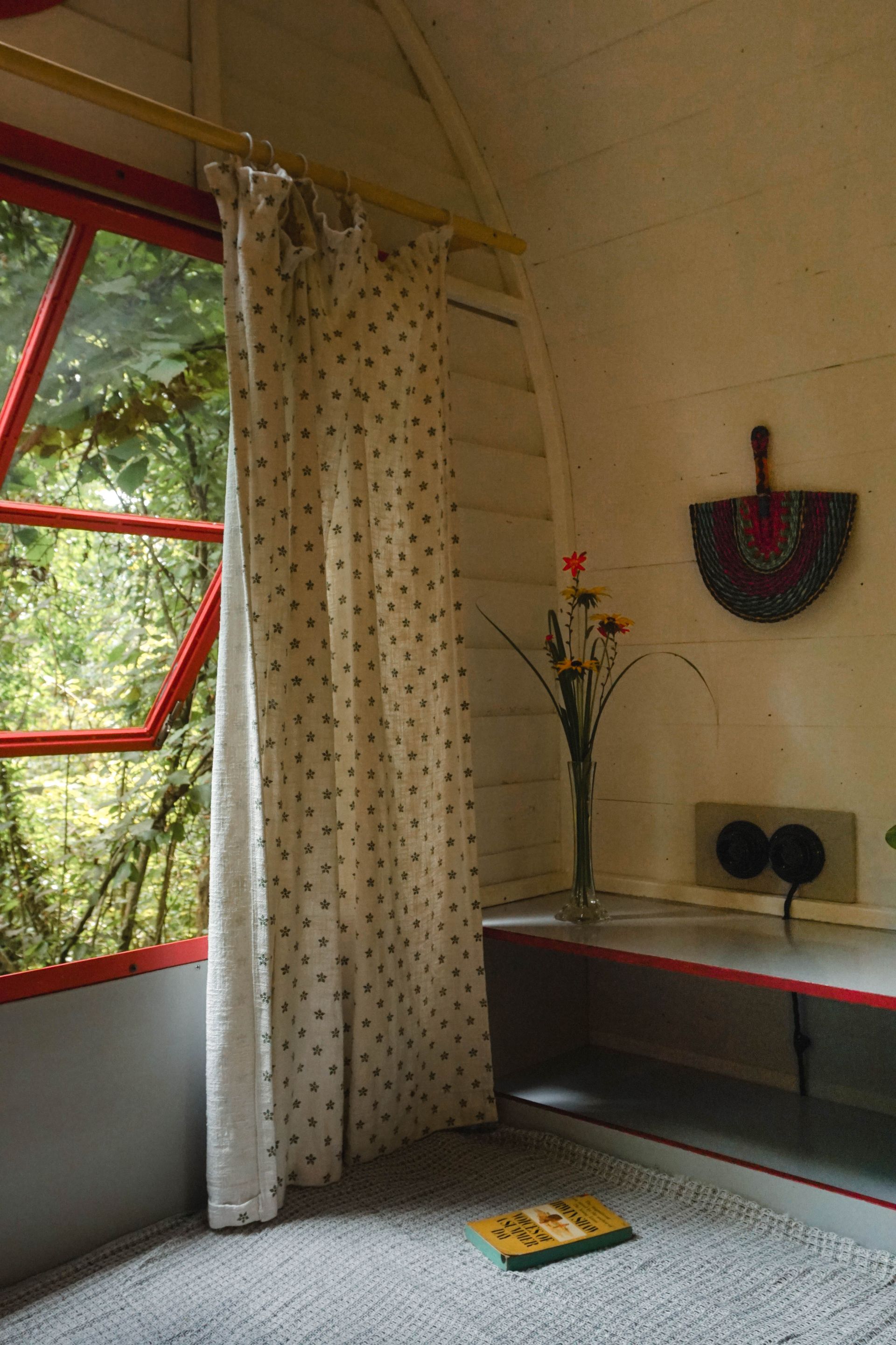 A room with polka dot curtains and a vase of flowers on the shelf