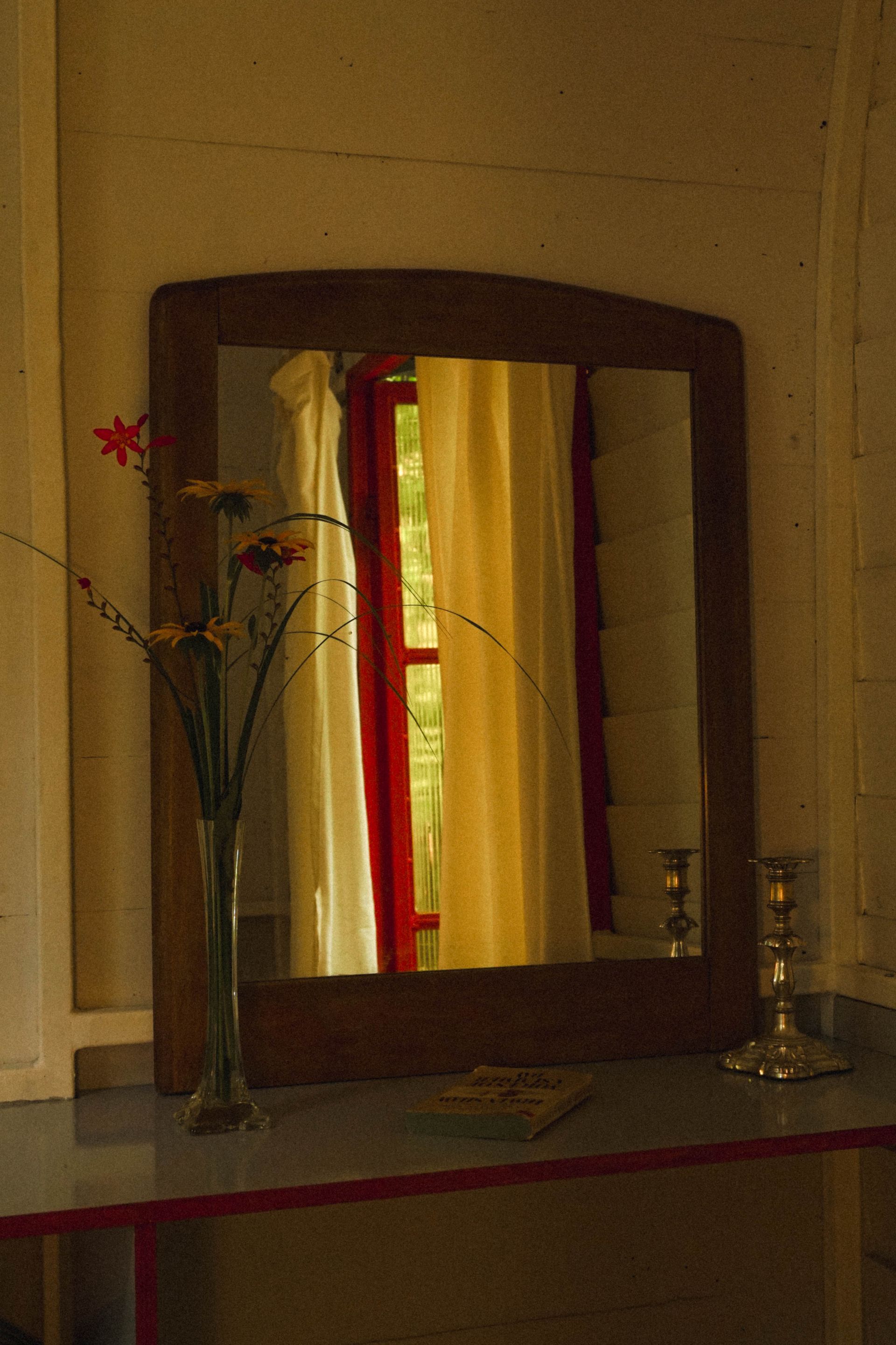 Room detail: A mirror with a vase of flowers 