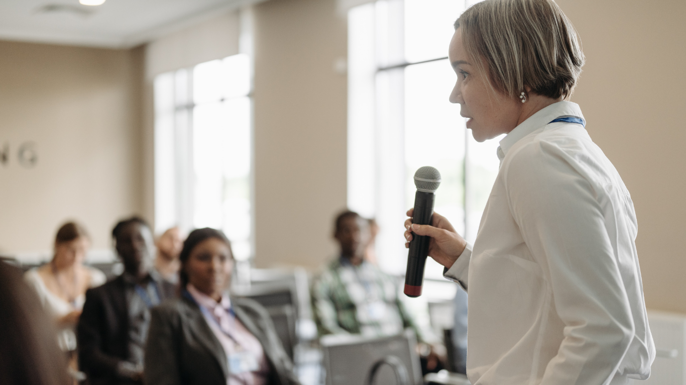 A woman is giving a presentation to a group of people in a library.