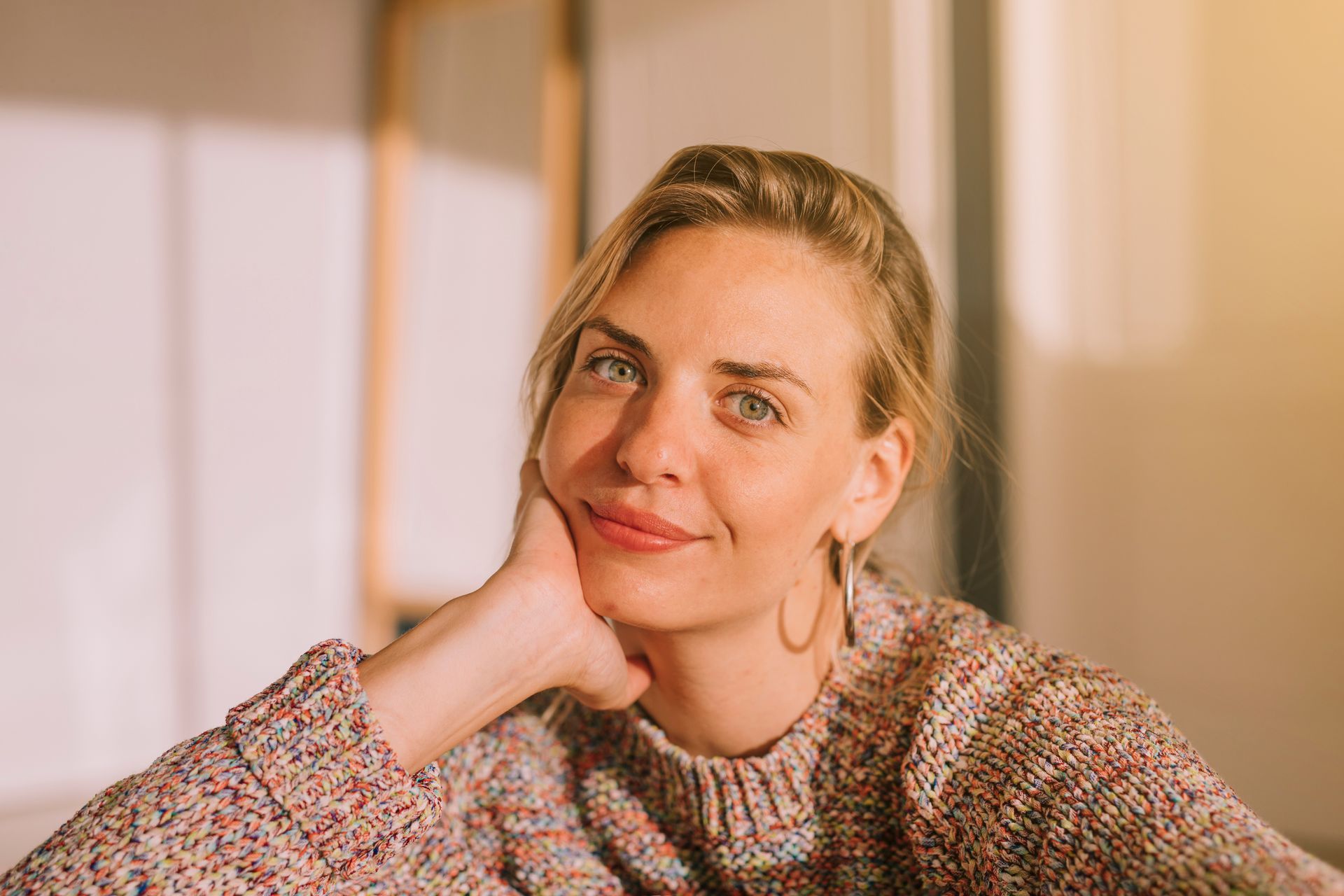 A woman is touching her face with her hands and smiling.