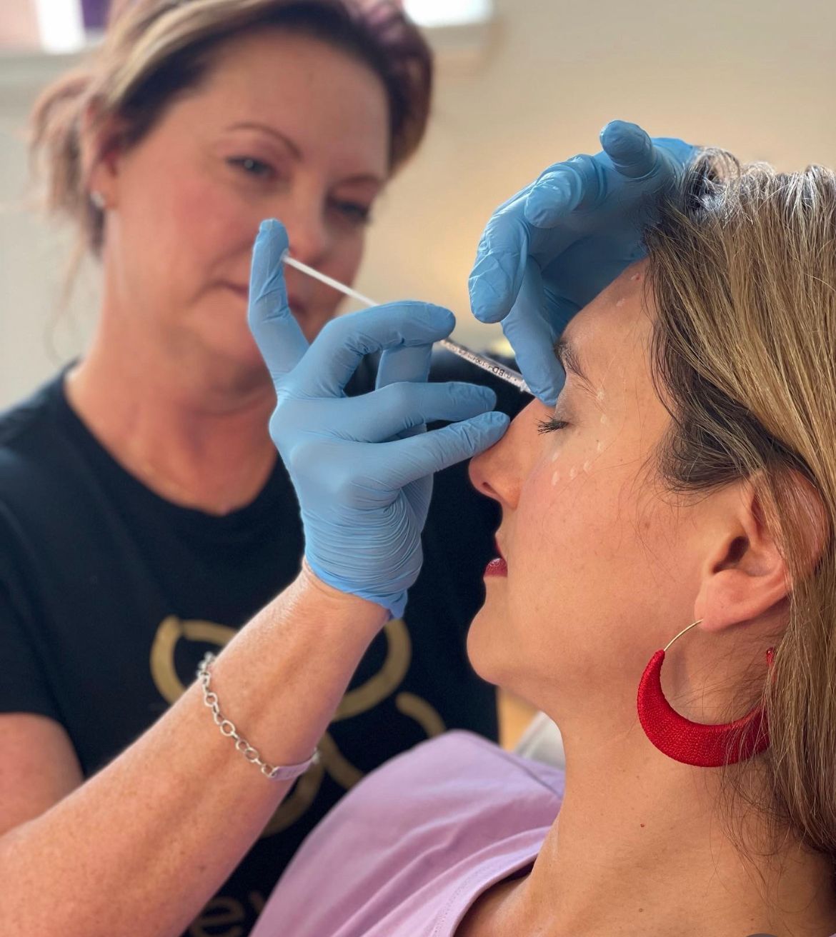 A woman is getting an injection in her eyebrows.