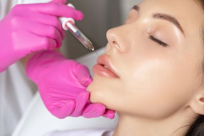 A woman is getting a botox injection in her lips.