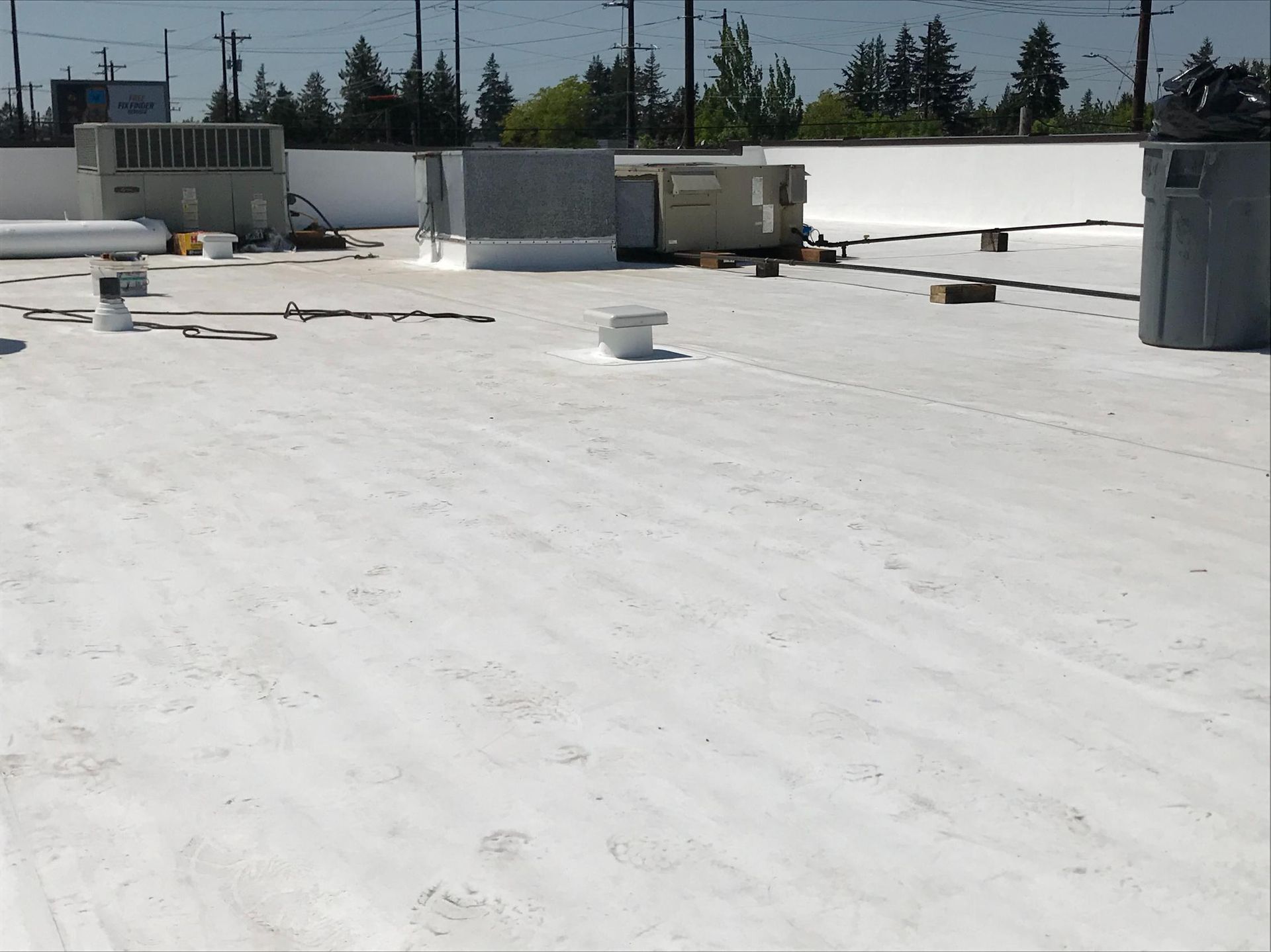 White commercial roof with HVAC units, vents, and utility boxes.