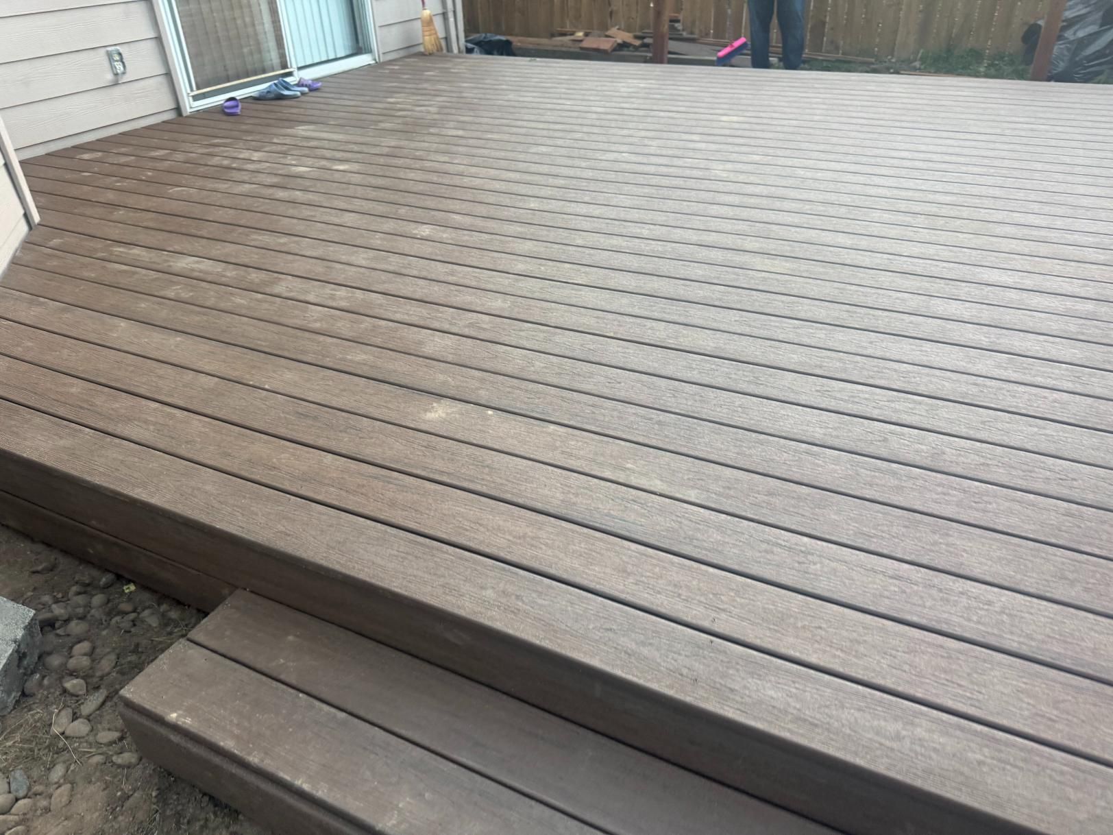 Brown composite deck with steps leading down to the ground.