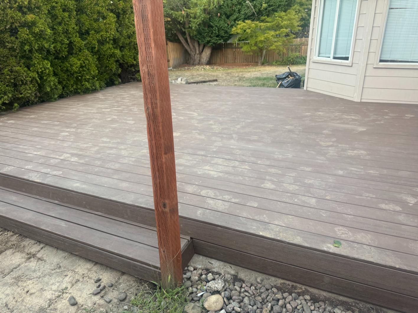 Wooden deck with steps, a brown support post, and a view of a yard.