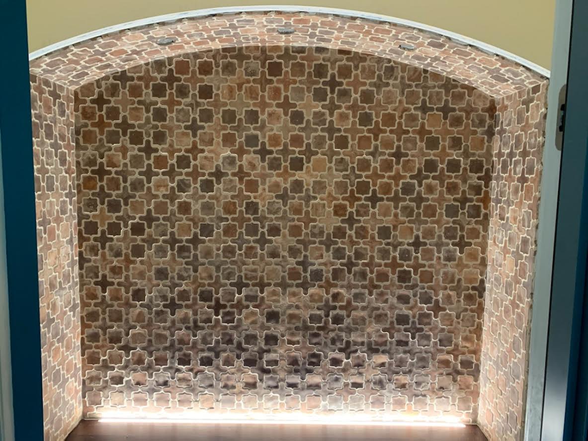 A brick wall with a pattern on it and a light behind it.