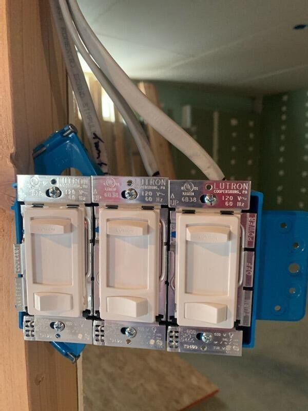 Three white light switches are installed in a blue box