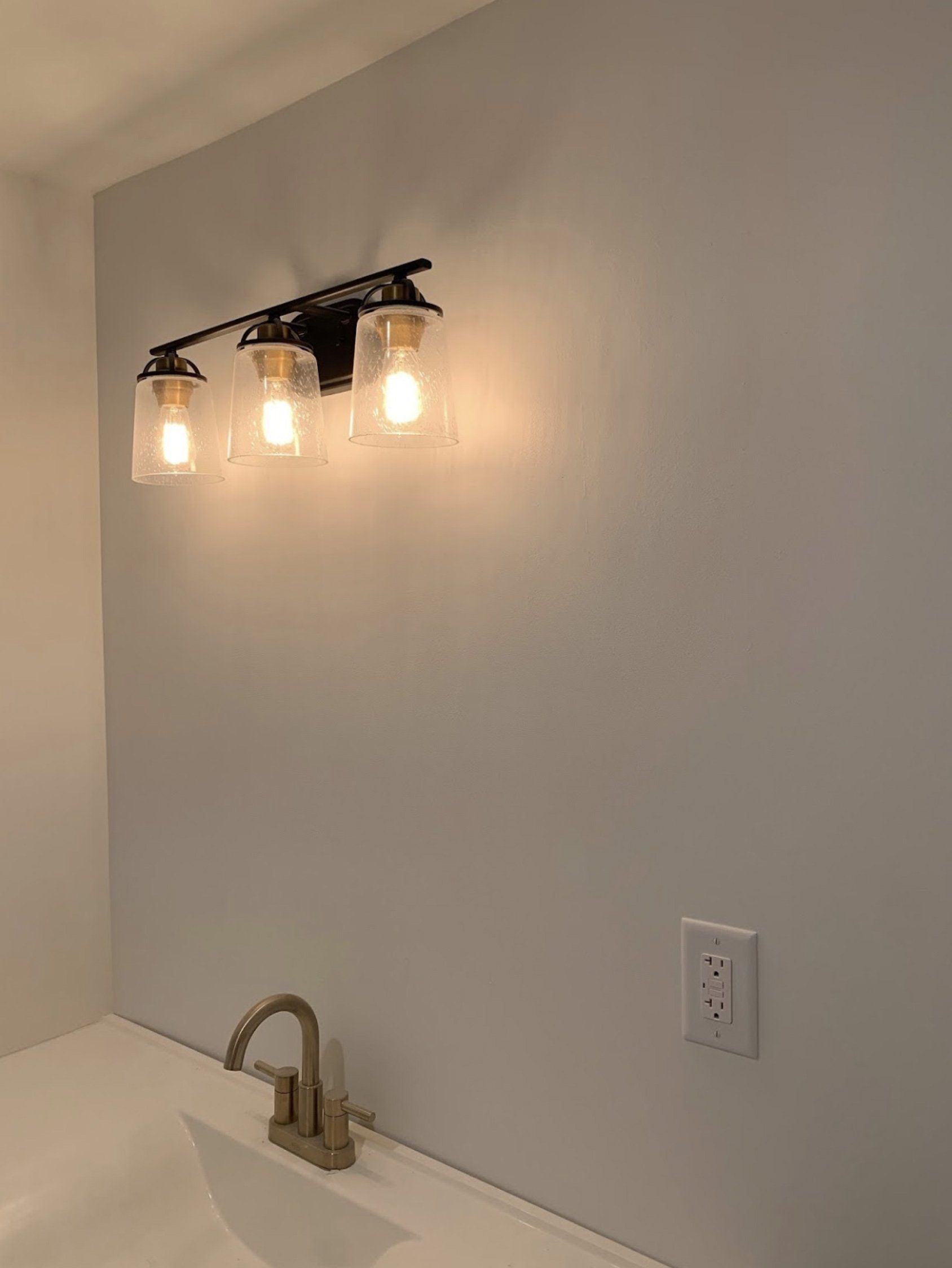 A bathroom with a vanity light and a sink.