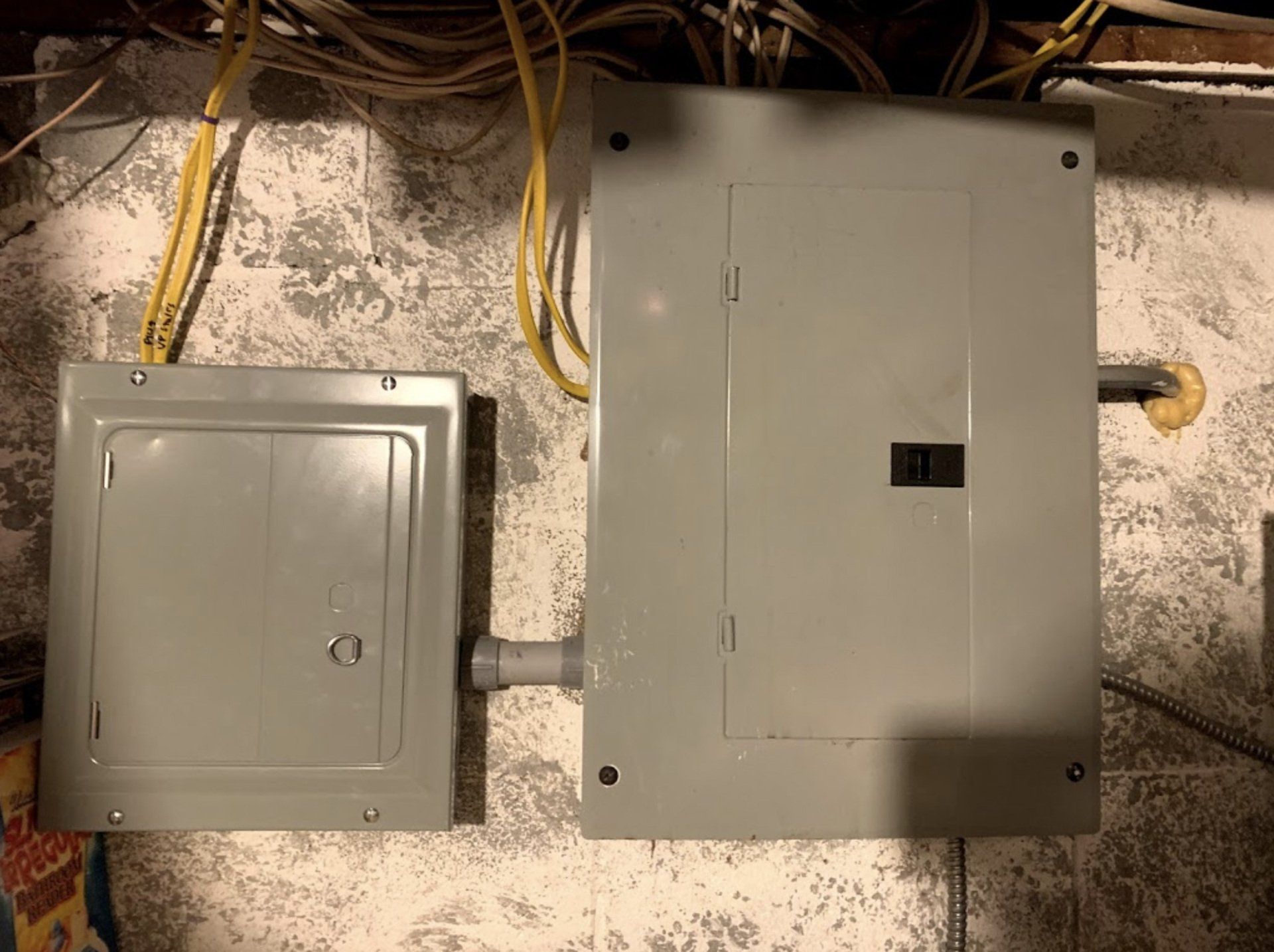 A gray electrical box is attached to a wall.