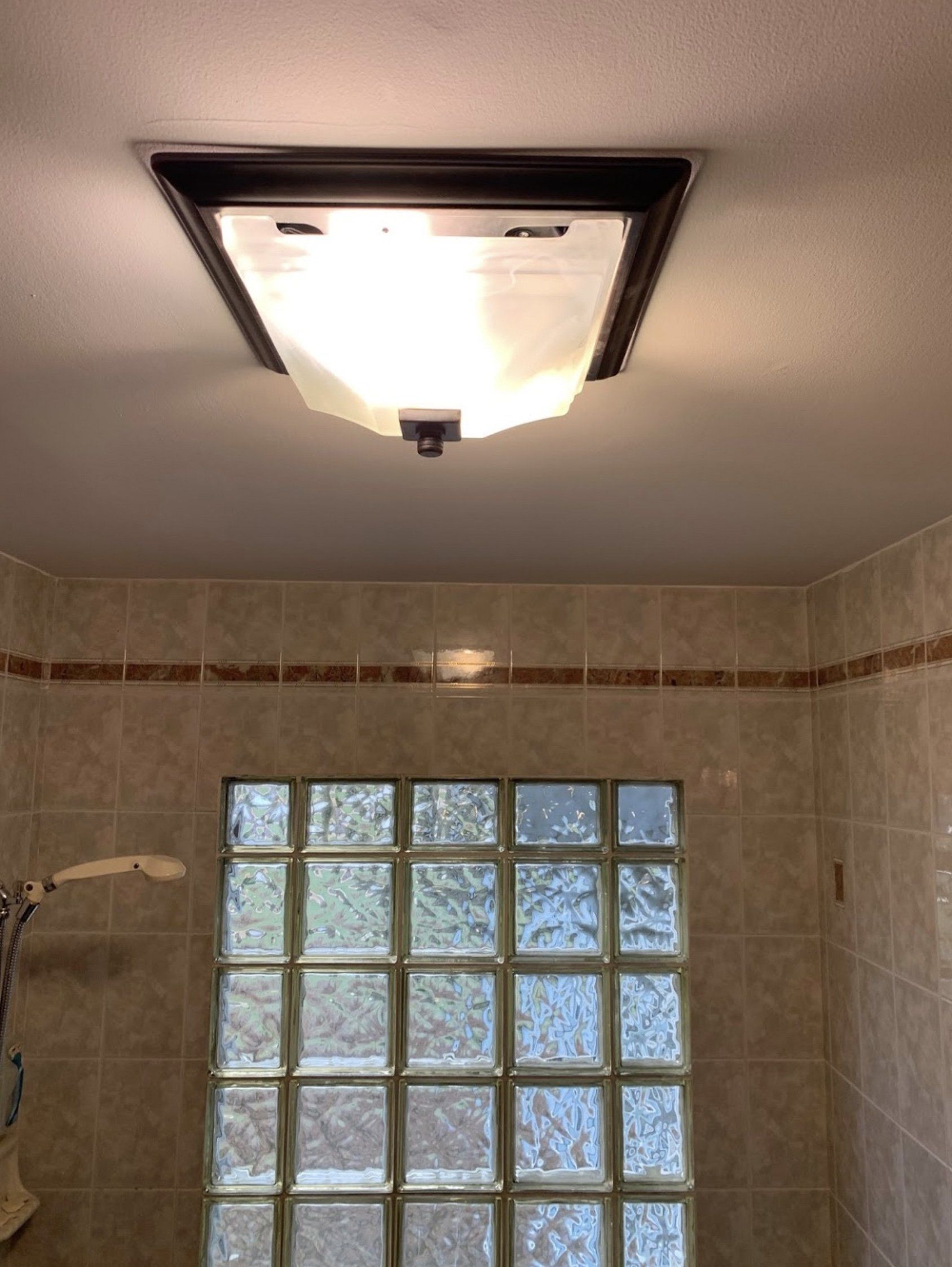 A bathroom with a ceiling light and a glass block window.