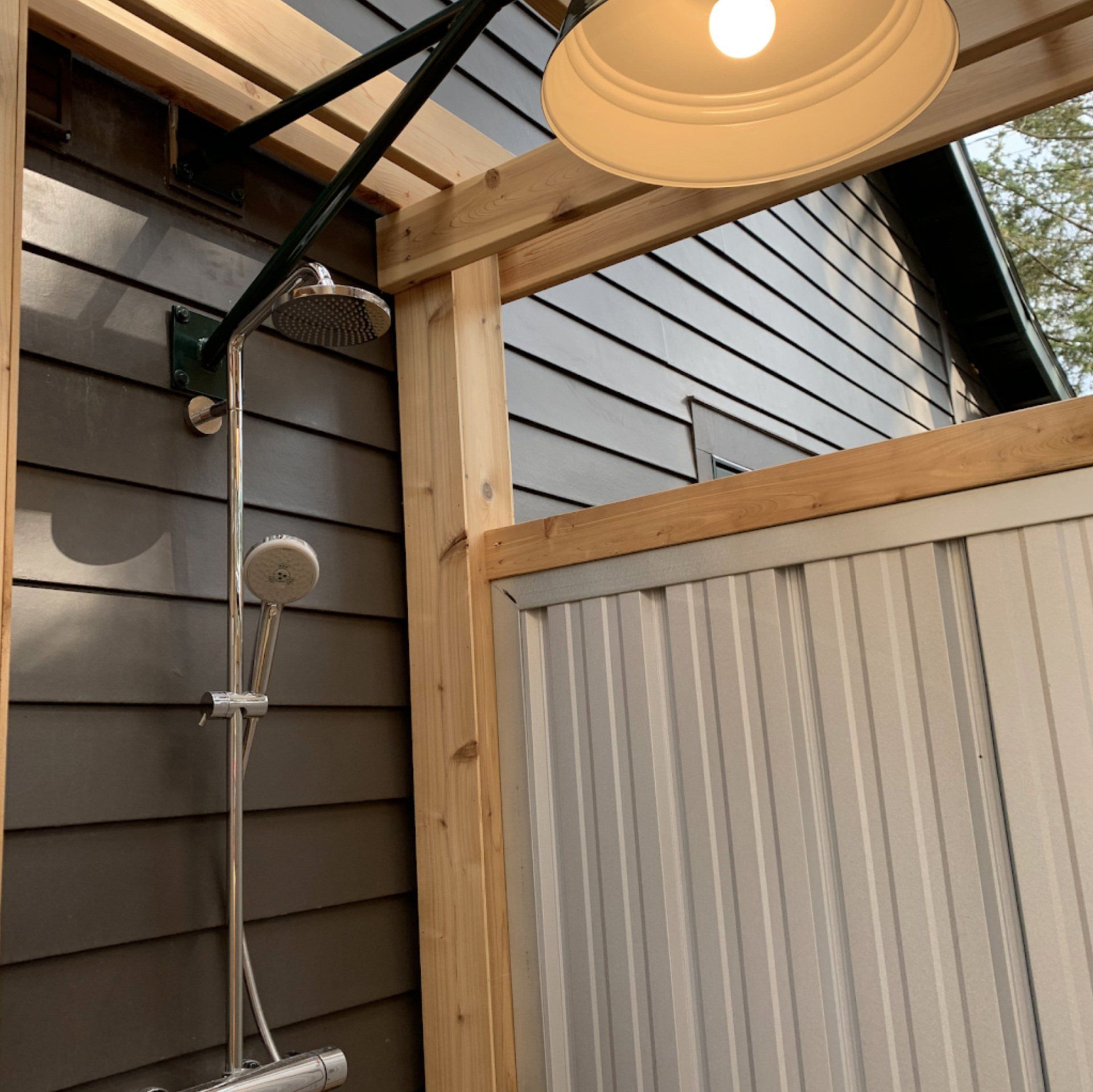 A outdoor shower with a light hanging from the ceiling