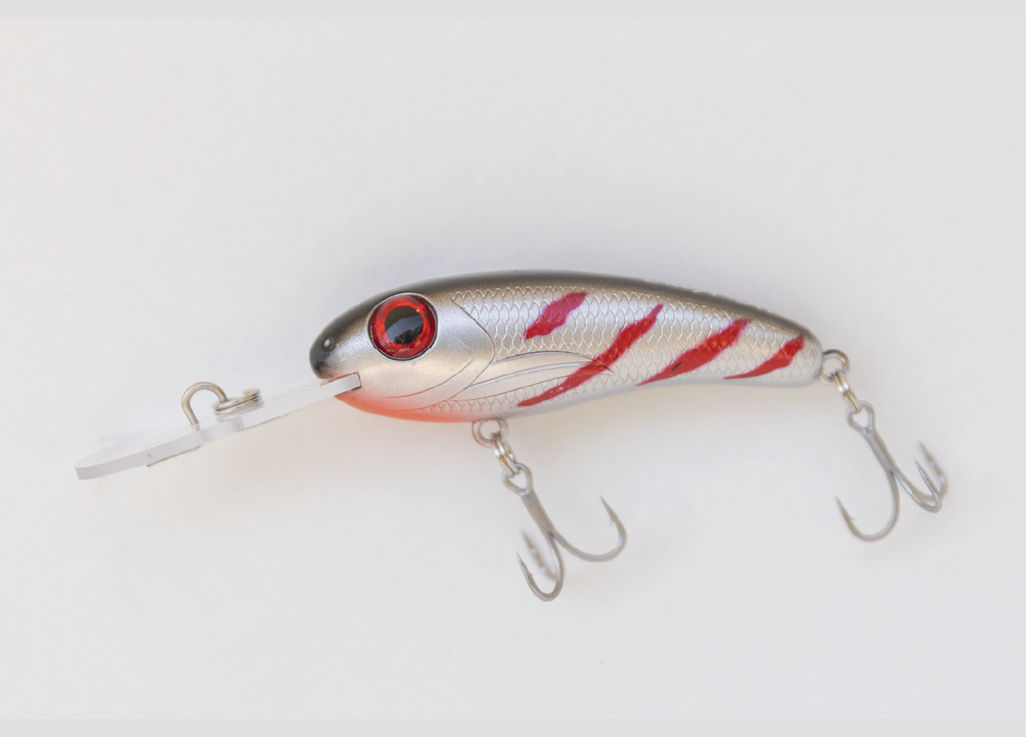 Silver and red striped fishing lure with two treble hooks and a plastic lip.