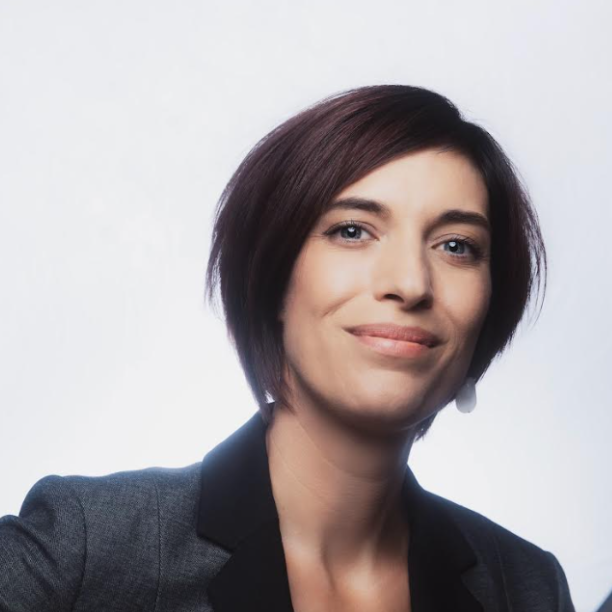 A woman with long brown hair is smiling for the camera
