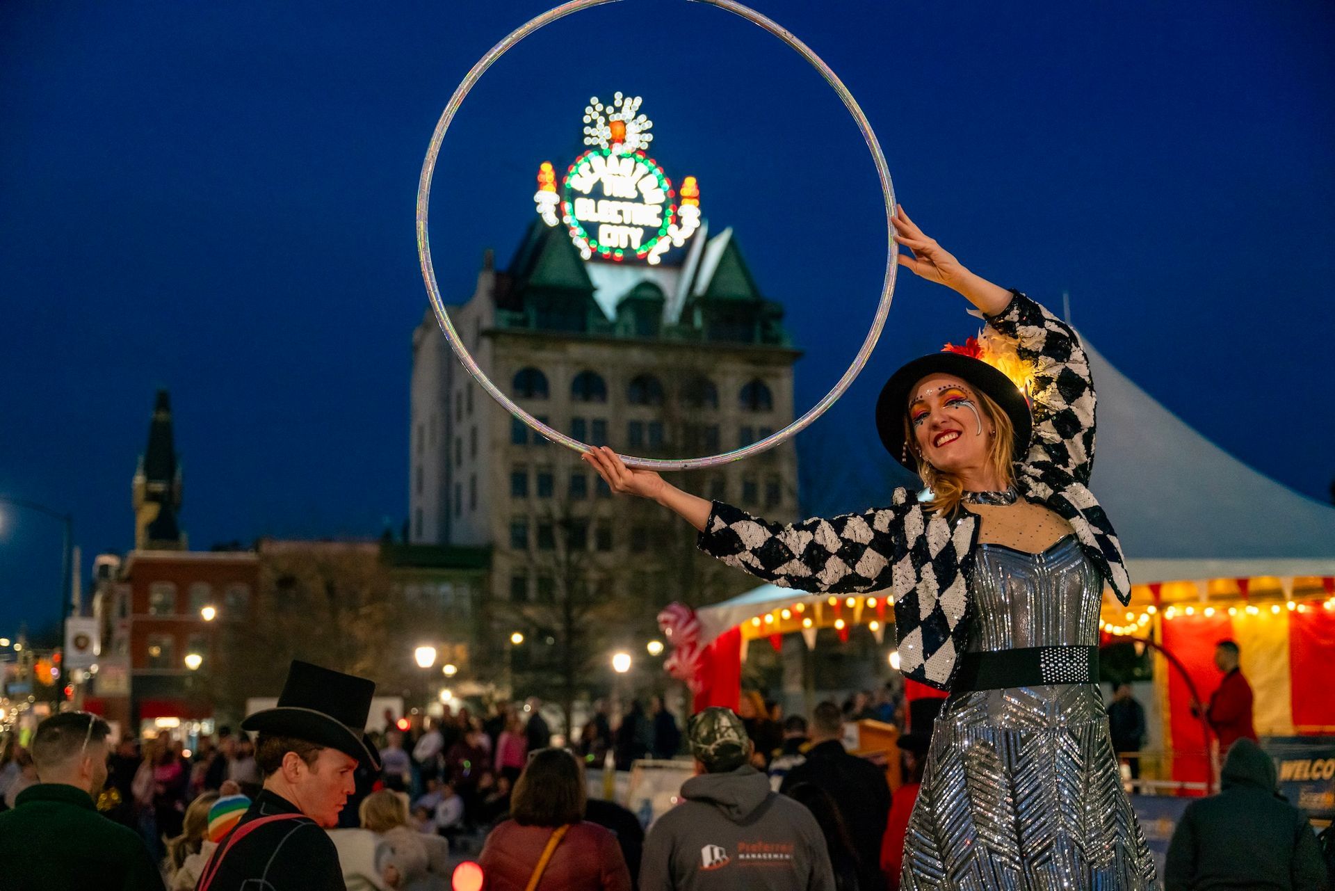 A woman is holding a hula hoop in front of a crowd of people.