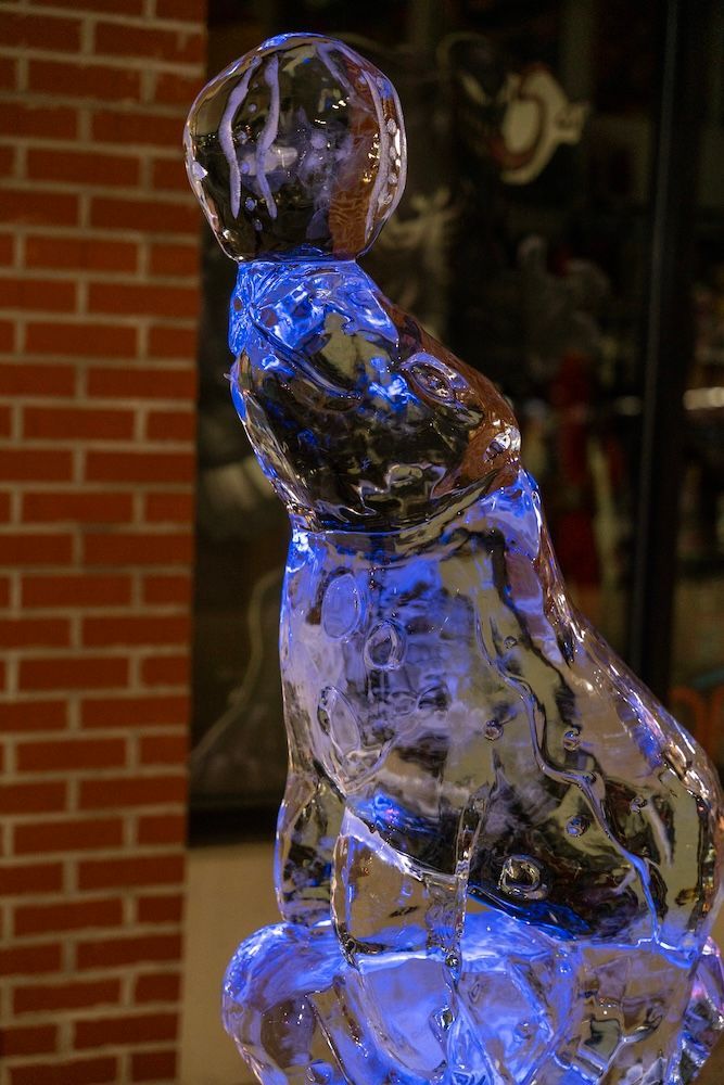 A close up of an ice sculpture of a seal holding a basketball.