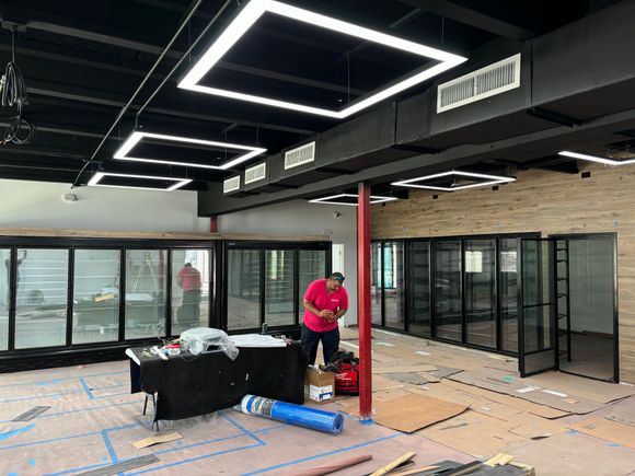 Two people in pink shirts are working on a ceiling.