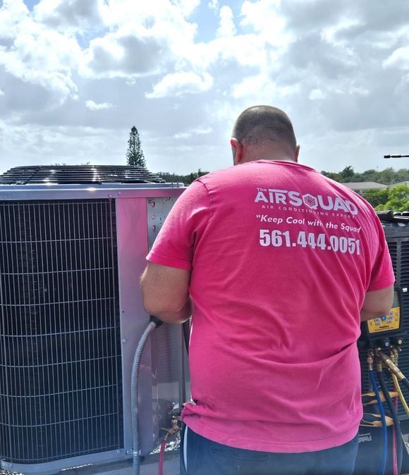 A man is carrying a large air conditioner on a cart.