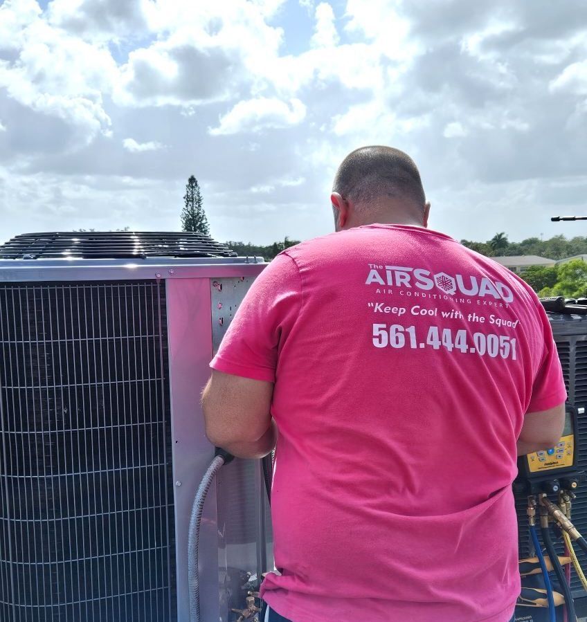 A man is working on an air conditioner on the roof of a building.