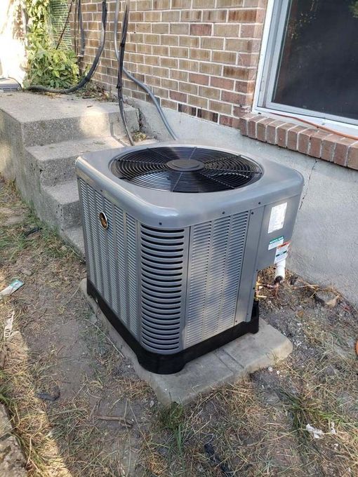 An air conditioner is sitting on the side of a brick building.