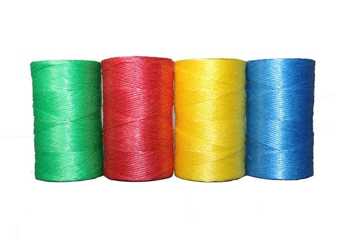 Cuatro rollos de hilo de colores están alineados en fila sobre un fondo blanco.