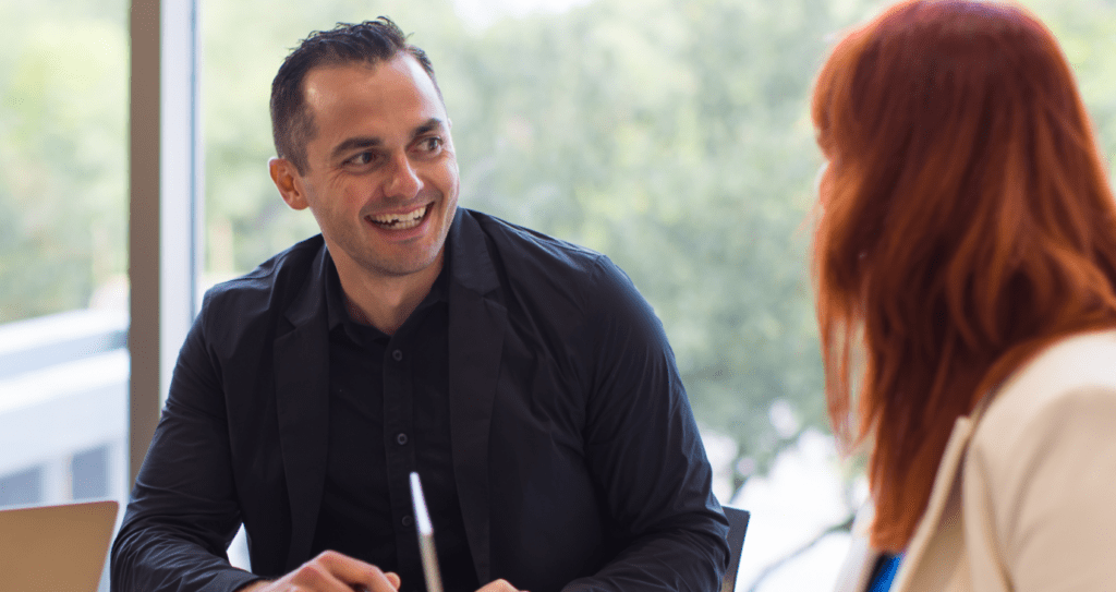 A man and a woman are sitting at a table having a conversation.