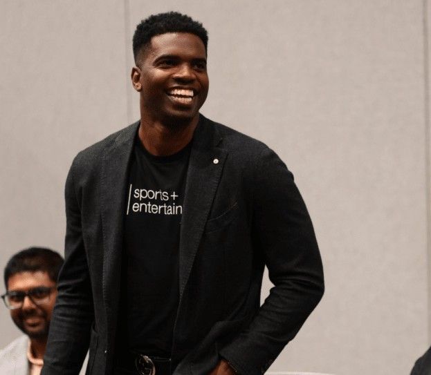 A man wearing a sports entertain t-shirt smiles