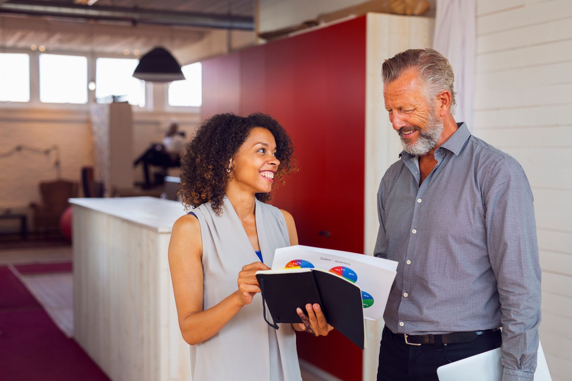 A man and a woman are standing next to each other in an office.