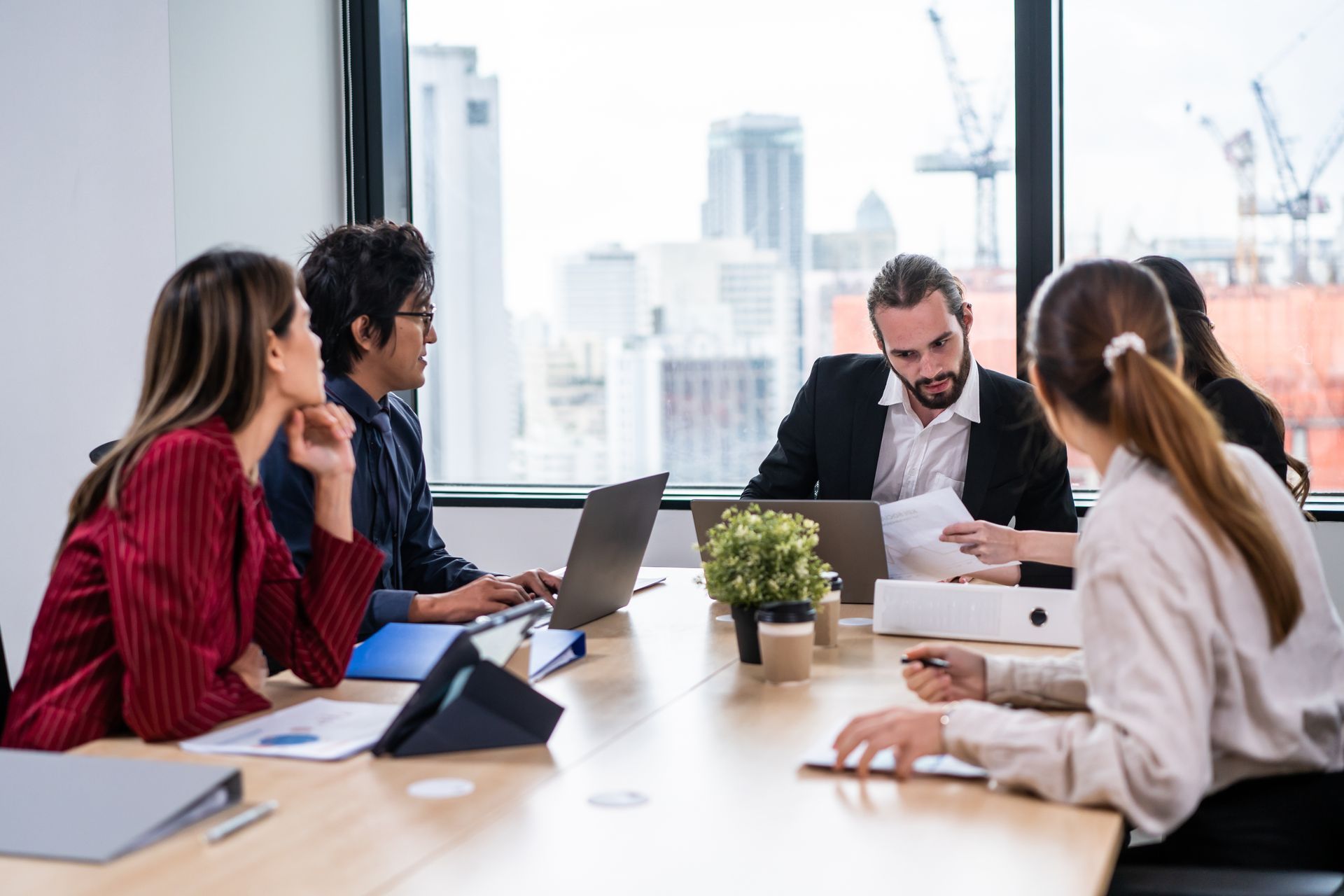A group of people are sitting around a table with laptops.