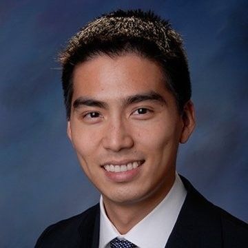 A man in a suit and tie is smiling for the camera.