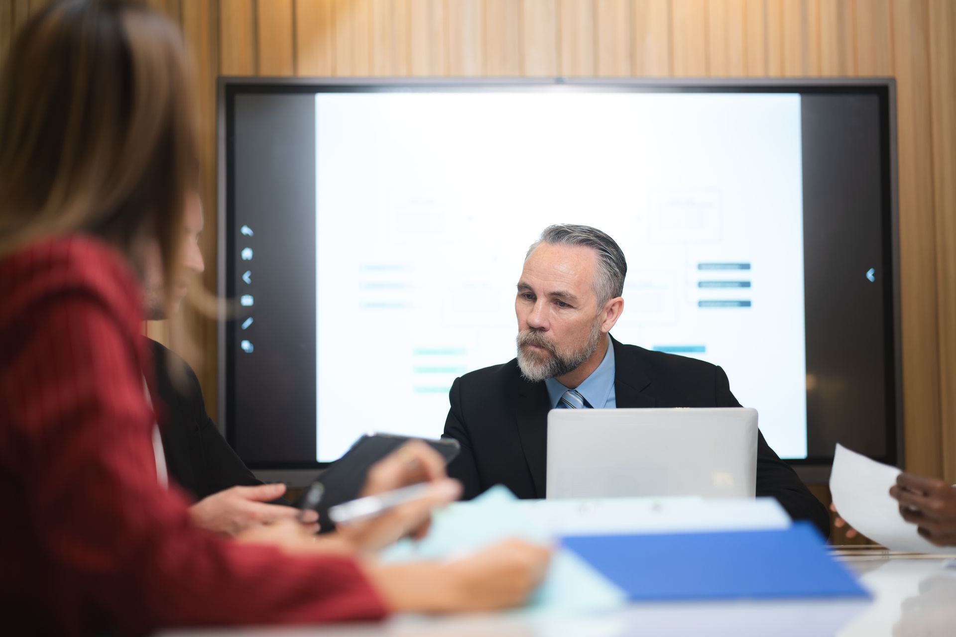 A man is sitting at a table with a laptop in front of a group of people.