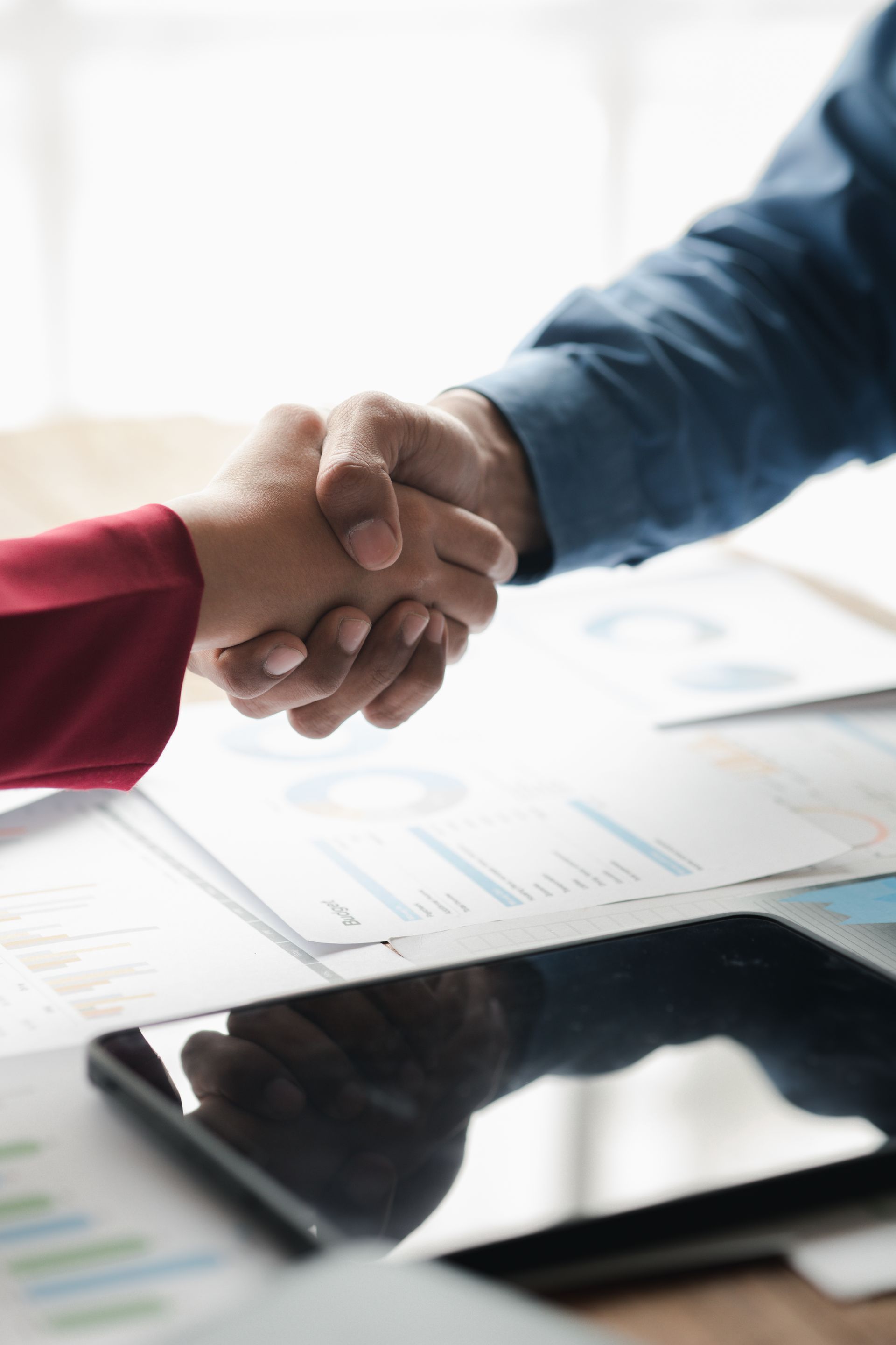 A man and a woman are shaking hands over a table.